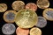 An assortment of Brazilian coins on a black reflective background with a American one ounce gold coin