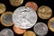 An assortment of Brazilian coins on a black reflective background with an American one ounce silver coin