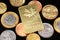 An assortment of Brazilian coins on a black reflective background with a Canadian one ounce gold ingot