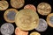 An assortment of Brazilian coins on a black reflective background with a gold physical Bitcoin