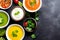 Assortment of colored vegetable cream soups. Dietary food. On a black stone background. Generative AI