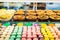 Assortment of Colorful macarons and tarts for sale in shop. Raws of sweets in candy shop storefront, cafe showcase. Traditional fr