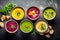 Assortment of colorful vegetable cream soups in black bowls. Top view.