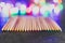 Assortment of coloured pencils on dark background with psychedelic multicolor string lights creating rainbow bokeh