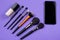 Assortment of cosmetic brushes near a bottle of foundation and mockup empty copy space mobile phone screen. E-learning, beauty