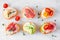 Assortment of cream cheese crostini hors d`oeuvres with a variety of toppings on a white marble background