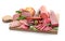 Assortment of delicious deli meats on wooden board, isolated on white