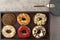 Assortment of donuts on wooden tray with dark plate and small fork and napkin