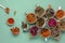 Assortment of dried relaxing tea herbs in colourful cups on mint green background with honey.