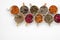 Assortment of dried relaxing tea herbs in colourful cups on white background close up.