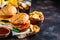 Assortment of fast food. Junk food background. Cheeseburgers, french fries, nachos, donuts, soda and nuggets on dark background