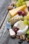Assortment of fresh cheeses, grapes and walnuts on wooden table