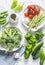 Assortment of fresh garden vegetables - asparagus, broccoli, beans, peppers, tomatoes, cucumbers, garlic, green peas on a light ba