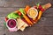 Assortment of fresh vegetables and hummus dip on a serving board, top view on rustic wood