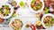 Assortment of fresh vegetables salads. Healthy food. On a white wooden background.