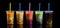 An assortment of fresh, vibrant boba arranged against a sleek black background. Plastic glasses filled with bubble tea