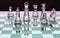 Assortment of glass chess pieces on board with pink and green sh