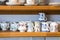 Assortment of hand painted ceramic floral pattern teacups with mugs on shelves