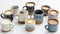 An assortment of handmade ceramic mugs and cups each holding a different type of artisan coffee