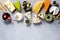 Assortment of hard, semi-soft and soft cheeses with olives, grissini bread sticks, capers, grape, on grey concrete