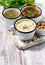 assortment of hot soups in mugs on wooden background, vertical