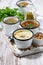 Assortment of hot soups in mugs on wooden board, vertical