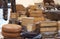 Assortment of italian organic cheeses made in mountain pastures, some with herbs, in a rural market. Salami on the background