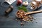 Assortment of legumes in wooden ladle, spilled on a wooden tabletop background, pepper grinder, onion, garlic and grater.