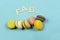 Assortment of multi-coloured macaroons on a blue background with the word fab