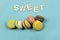 Assortment of multi-coloured macaroons on a blue background with the word sweet