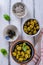 Assortment of olives with herb and sea salt on white wooden bac