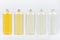 Assortment of plastic tall bottles with cosmetic essential oil of different pastel pale colors, silver cap mockup on white.