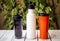 Assortment of refillable plastic and stainless steel water bottles on table against blurred background