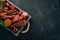 Assortment of sausages and snacks in a wooden box. Sausage Fuet, salami, paperoni. On a black background.