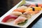 Assortment sushi on a white plate over the black table