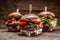 Assortment of three various burgers ready to be plated, with a dark wooden background