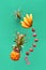 Assortment of tropical fruits, levitation on green background. Pineapple, lichee and banana - flying exotic fruits in yellow,