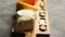 Assortment of various kinds of cheeses served on wooden board with fork and knives