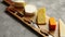 Assortment of various kinds of cheeses served on wooden board with fork and knives