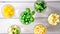 Assortment of yellow and green cut vegetables in shot glass on white background.