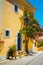 Assos village. Traditional pink colored greek house with bright blue door and windows. Fucsia plant flowers around entrance