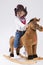 Assured Calm Little Caucasian Girl in Cowgirl Clothing On Symbolic Horse Against White Background