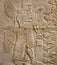 Assyrian wall relief of a winged genius with cuneiform