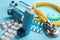 Asthma inhalers, stethoscope and pills on color background