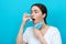 Asthma. Portrait of young woman takes a medical mask to make the inhalation of medication. Blue background. Copy space