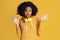 Astonished african american young woman dressed in casual clothes and headphones over yellow background.