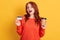 Astonished buyer finding offer online, holding take away coffee and credit card, has surprised facial expression, lady with red