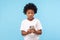 Astonished cute little boy with curly hair reading message on smartphone and expressing amazement shock