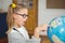 Astonished pupil pointing on globe in a classroom