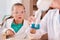 Astonished schoolgirl in protective eyeglasses looking at blue liquid substance